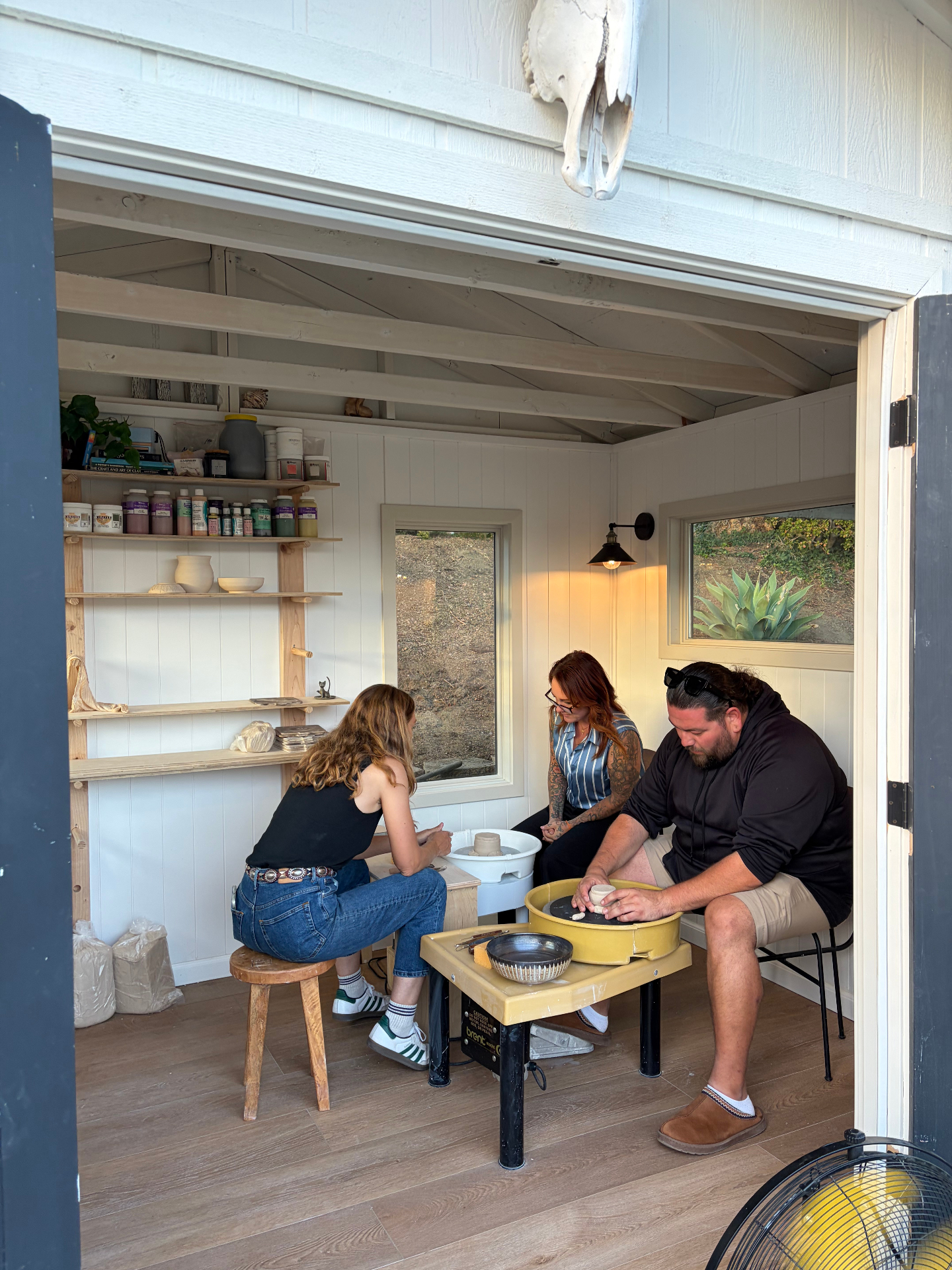Three students working on pottery wheels inside the studio