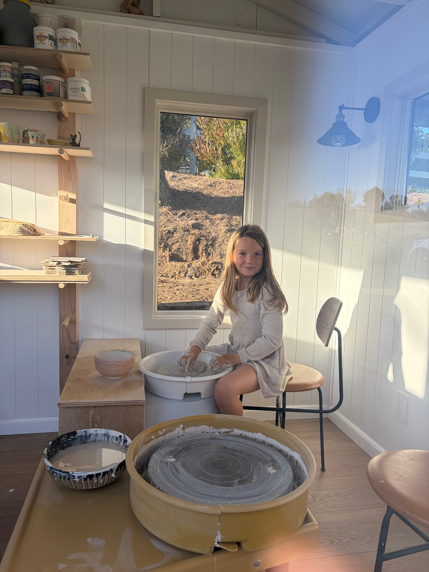 A child shaping clay on the pottery wheel in warm afternoon light