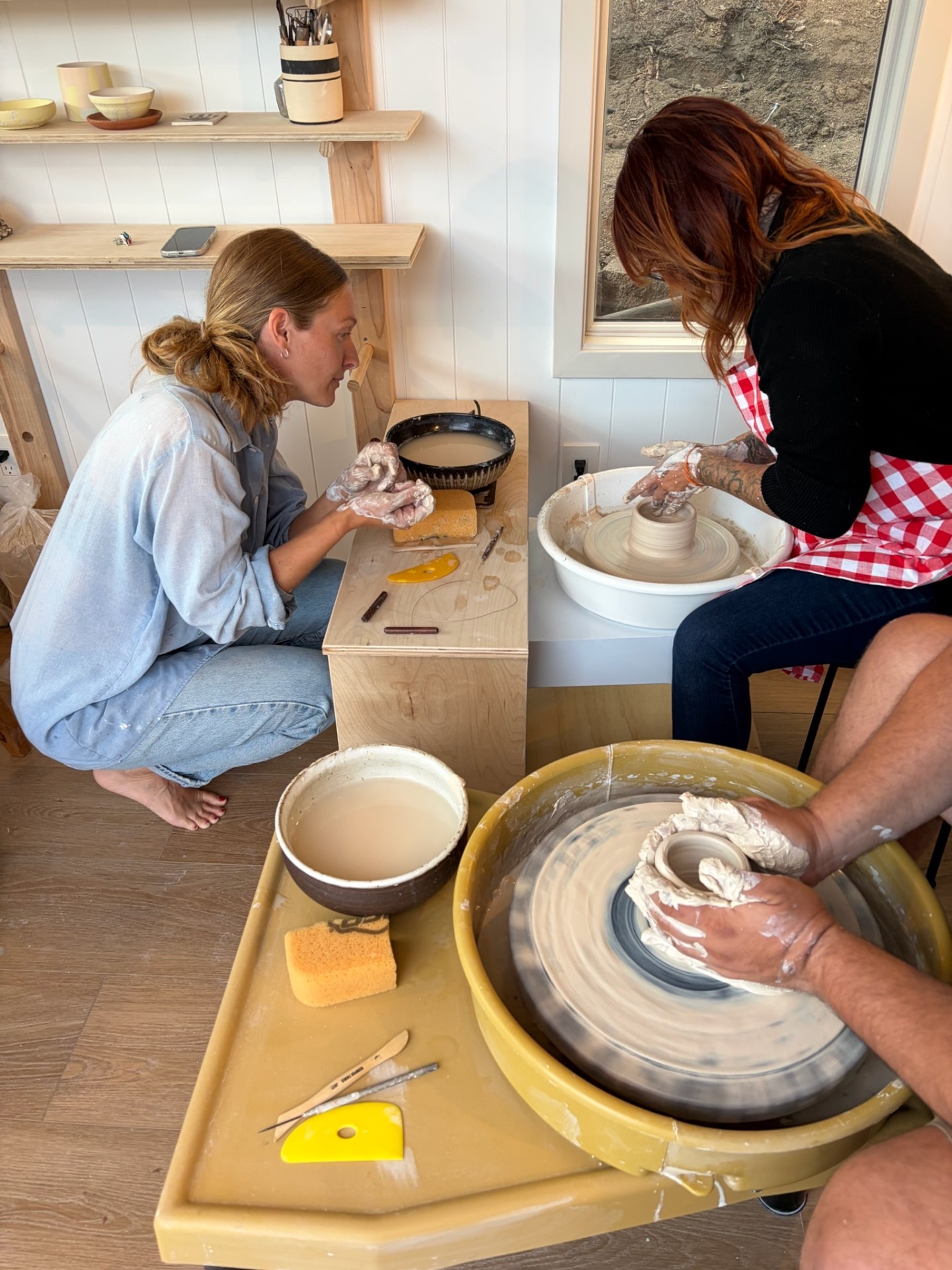 Two students centering clay on the pottery wheel
